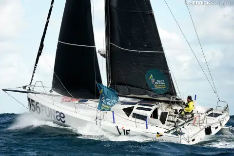 Le Class40 au portant, le skipper en ciré jaune au cockpit