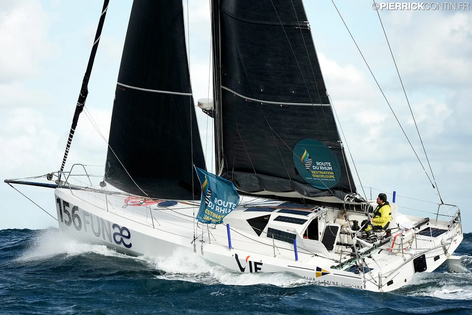 Le Class40 au portant, le skipper en ciré jaune au cockpit