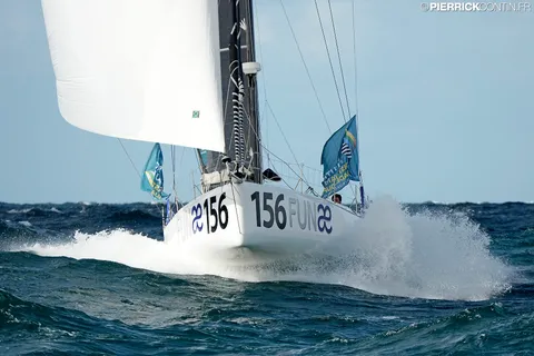 Le Class40 sous voile d'avant blanche, l'étrave dans la gerbe