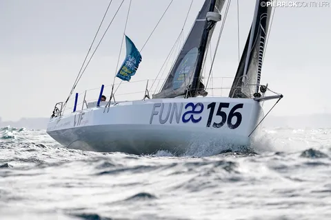 Le Class40 vu de l'avant, la coque blanche portant le nom FUNAE, dans une mer agitée
